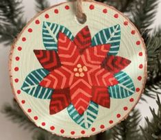 a wooden ornament hanging from a christmas tree with red and blue designs on it