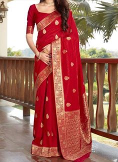 a woman in a red sari standing on a balcony with palm trees behind her