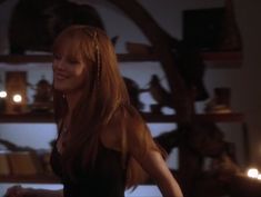 a woman with long red hair standing in front of a shelf full of books and candles