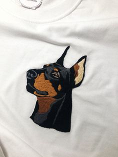 a white shirt with a black and brown dog embroidered on it