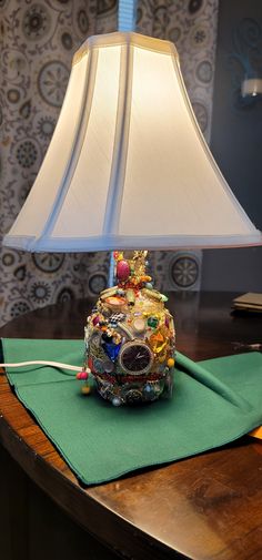 a lamp that is sitting on top of a green table cloth next to a wooden table