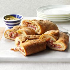 several sandwiches cut in half on a cutting board next to plates and bowls with condiments