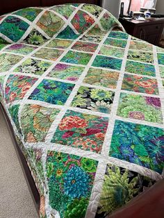 a bed with a colorful quilt on top of it