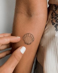 two women with tattoos on their arms and one has a shell tattoo on her arm