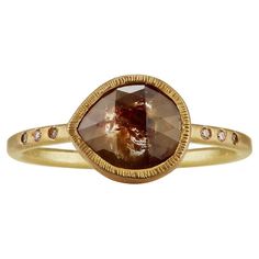 a yellow gold ring with an oval shaped brown diamond in the center and diamonds around it