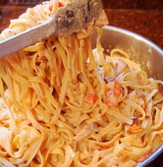 a spoon full of pasta being lifted from a pan with the noodles in it to be eaten