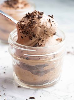 two jars filled with dessert and one has a spoon in it to scoop out some ice cream