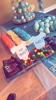 a table topped with lots of cupcakes covered in frosted icing and candy