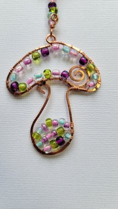 a wire wrapped necklace with glass beads and gold tone pendant on a white background,