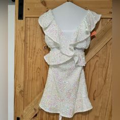 a white dress hanging on a wooden door with sequins all over the skirt