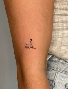 a person with a small dog tattoo on their left arm and the other arm behind them