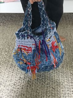 a woman is holding a purse made out of old jeans and crocheted yarn