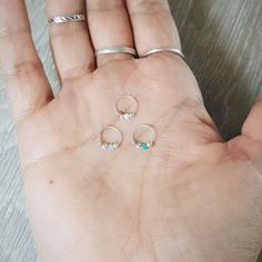 a person's hand with three rings on it and two small stones in the middle