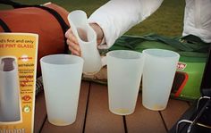 a table topped with cups and utensils on top of a wooden table next to a bag