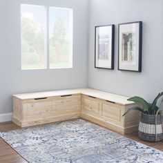 a corner bench in the corner of a room with two framed pictures on the wall