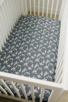 a baby crib with a blue and white horse print sheet in the bottom half