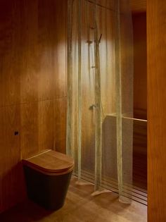 a bathroom with wooden walls and flooring next to a shower curtain that has mesh netting on it