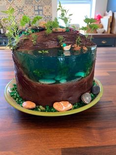 a cake that is sitting on top of a table with rocks and plants in it