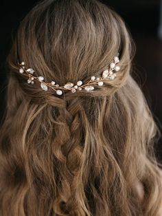 a woman with long hair wearing a gold headband and pearls on it's side