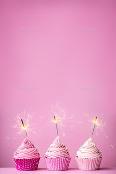 three cupcakes with pink frosting and sparklers