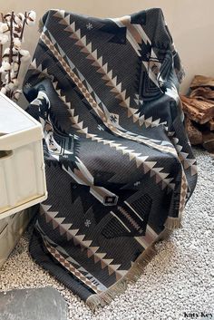 a black and white blanket sitting on top of a floor next to an open box