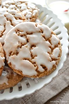 two cookies covered in white icing sitting on top of a plate next to some apples