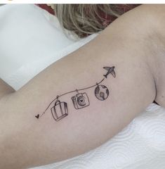 a woman's arm with an airplane and suitcases tattoo on her left shoulder