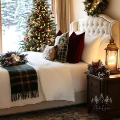 a bedroom decorated for christmas with a tree and wreath on the bed, candles in front of the window