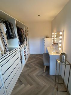 a dressing room with white walls and wooden flooring, lighted by lights on the wall