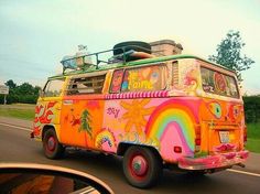 an old van painted in bright colors driving down the road