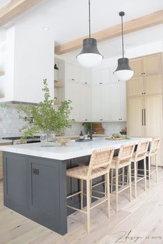 a kitchen island with four stools next to it and a potted plant in the center