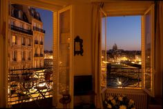 an open window overlooking the city lights and buildings in paris, france at night time