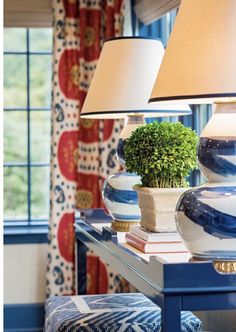 a blue table with two lamps on top of it and a potted plant in the middle