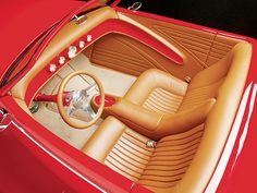 the interior of a red sports car with tan leather seats and steering wheel, shown from above