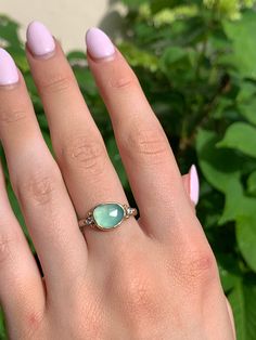 A seafoam green chrysoprase is set in 14k yellow gold a top a sterling silver seagrass band. Accented with small handmade gold beads. Approx stone size: 12mm x 10mm Approx stone weight: 2.9cts Mohs Hardness: 6-7 This one of a kind piece is handmade in Emily's Hudson Valley studio. If you have questions about sizing, shipping or need help deciding please reach out to us! Yellow Gold Chalcedony Jewelry For Anniversary, Chalcedony Yellow Gold Jewelry For Anniversary, Anniversary Yellow Gold Chalcedony Jewelry, Fine Jewelry In Yellow Gold With Chalcedony, Sterling Silver Turquoise Ring With Yellow Gold Gemstone, Turquoise Gemstone Ring In Yellow Gold Sterling Silver, Sterling Silver Turquoise Ring In Yellow Gold, Elegant Adjustable Green Opal Ring, Yellow Gold Chrysoprase Emerald Ring For Anniversary