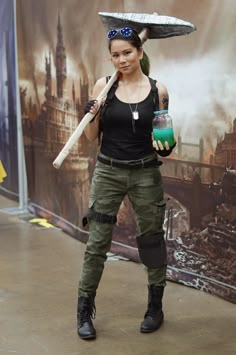 a woman in black shirt and green pants holding a baseball bat