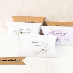 three boxes with wedding favors in them sitting on a white surface next to each other