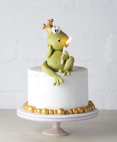 a cake decorated with a frog holding a lit candle