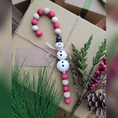 a snowman made out of plastic beads and some pine cones on top of a cardboard box