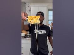 a man is holding up some food in his hand while he stands in the kitchen