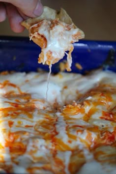 someone is taking a slice of pizza from the casserole dish with cheese and sauce