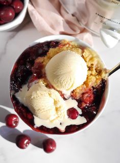 a bowl filled with ice cream and cherries on top of a white countertop