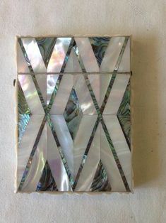 an art piece made out of mother of pearl in the shape of a diamond on a white surface