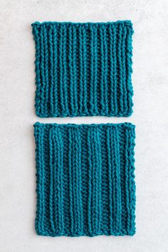 two blue knitted squares sitting next to each other on top of a white surface