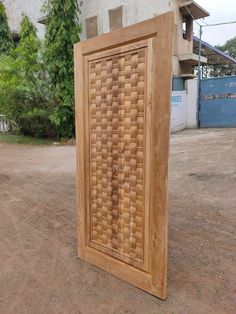 a wooden frame sitting in the middle of a dirt field next to a tall building