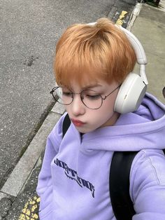 a young boy wearing headphones sitting on the side of a street next to a sidewalk