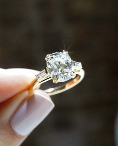 a person is holding a ring with a diamond in it's center and two baguetts on the side