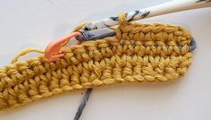 the crochet hook is next to an orange handled knitting needle on a white surface