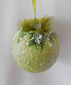 a green ornament hanging on a white wall with snowflakes and mist