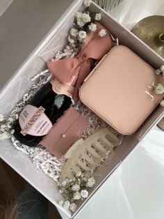 an open box containing a pink purse, bottle and hair brush with flowers on the side